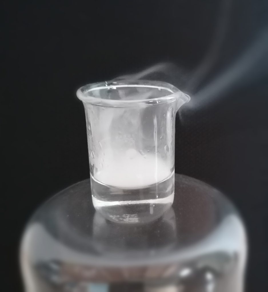 Trifluoroacetic acid in a beaker. The fumes can be clearly seen.